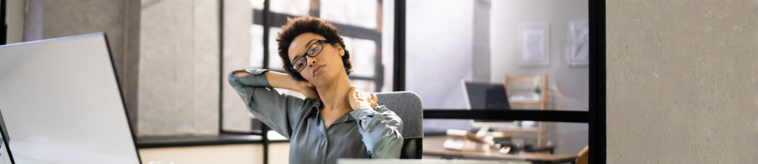 Woman experiencing neck pain while working at a computer, a common symptom of cervical disc problems.