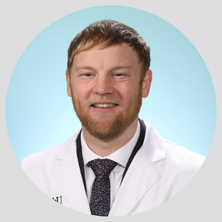 Photo of physician assistant Ace Camfield on a teal background in a white coat.